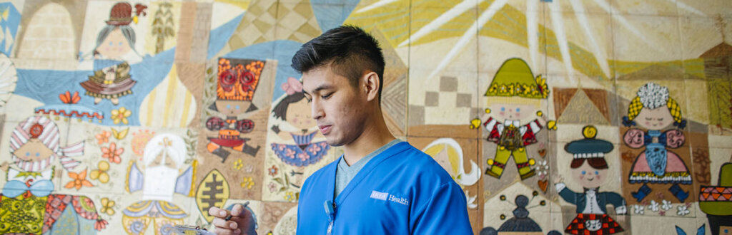 Young medical professional standing in front of colorful mural